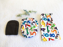 Load image into Gallery viewer, Nappy with design of brightly coloured number creatures on a soft white background.