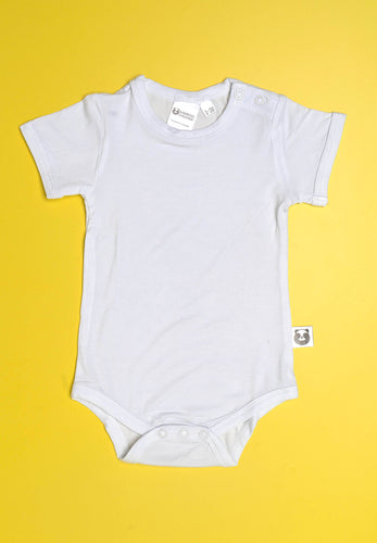 A beautiful high quality bright white short sleeve onesie against a bright colored backdrop. A small white label sits out from the torso side with a cartoon black and white panda covering his eyes playfully.