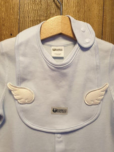 Baby blue bib, with pearly white wings, sat on top of a baby blue angel onesies, on a wooden coat hanger.  