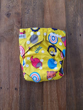Load image into Gallery viewer, Bold designed nappy, in sunshine yellow with cartoon animal faces including a monkey, giraffe and elephant, amongst others. 