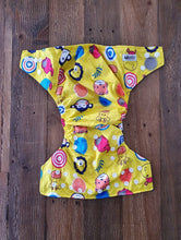 Load image into Gallery viewer, Bold designed nappy, in sunshine yellow with cartoon animal faces including a monkey, giraffe and elephant, amongst others. 