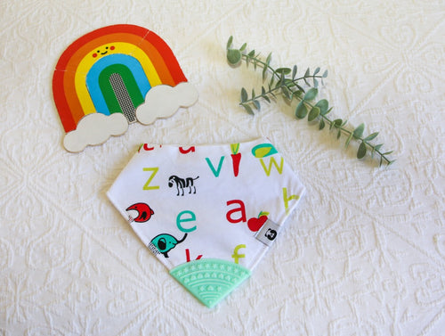 White bib with modern green and red letters and animal images, with a mint green teething tip.