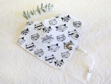 Load image into Gallery viewer, White bib with cool black and white racoon faces. White silky material coming out of bib to attach dummy/ comforter to. 