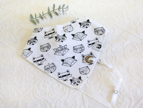 White bib with cool black and white racoon faces. White silky material coming out of bib to attach dummy/ comforter to. 
