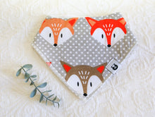 Load image into Gallery viewer, Big bold foxes faces on a grey and white spotted background bib.