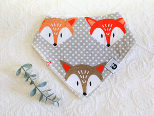 Big bold foxes faces on a grey and white spotted background bib.