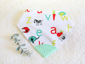 White bib with modern green and red letters and animal images, with a mint green teething tip.