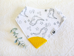  white bib with pencil black T-Rex drawings, with a yellow teething tip.