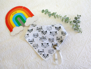 White bib with cool black and white racoon faces. White silky material coming out of bib to attach dummy/ comforter to. 