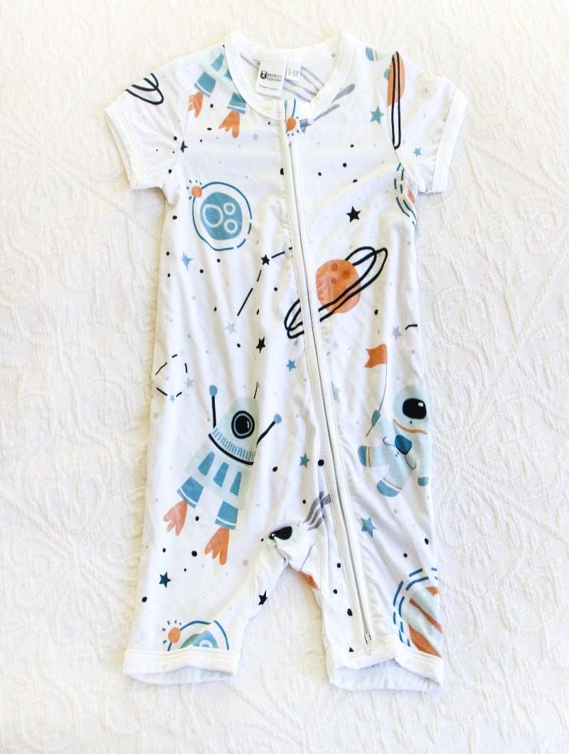 White onesie with blue planets and rockets, and beige and black accents depicting planets and stars/