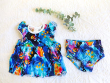 Load image into Gallery viewer, Bold and beautiful watercolour style romper, consisting of a dress and matching knickers. In shades of indigo, turquiose and midnight blue, with hot pink and sunny orange fireflies in jars.