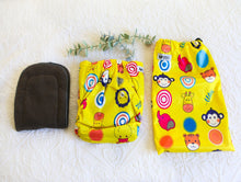 Load image into Gallery viewer, Bold designed nappy, in sunshine yellow with cartoon animal faces including a monkey, giraffe and elephant, amongst others. 