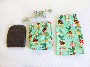 Mint green nappy with big smiley giraffes wearing dark green scarfs. 