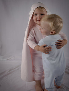 Babies cuddling, showing blue and pink angel wings onsies.