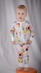 Baby stood on orange cushion, wearing beautiful water colour onesie